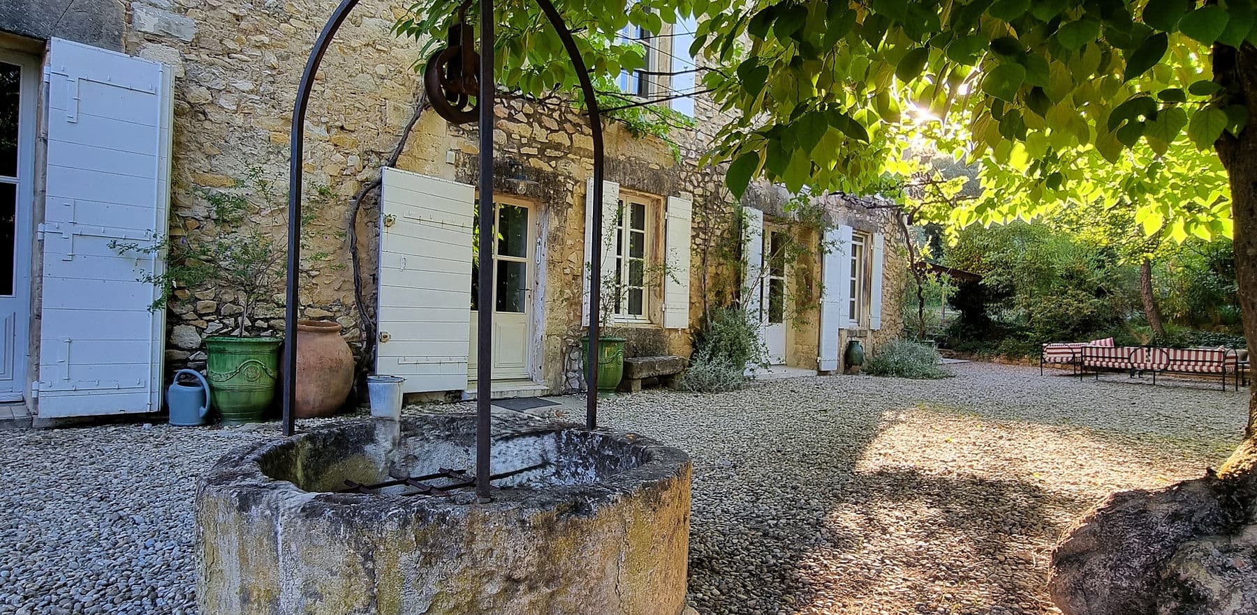 Façade en pierre du Mas Saint Michel et puits provençal